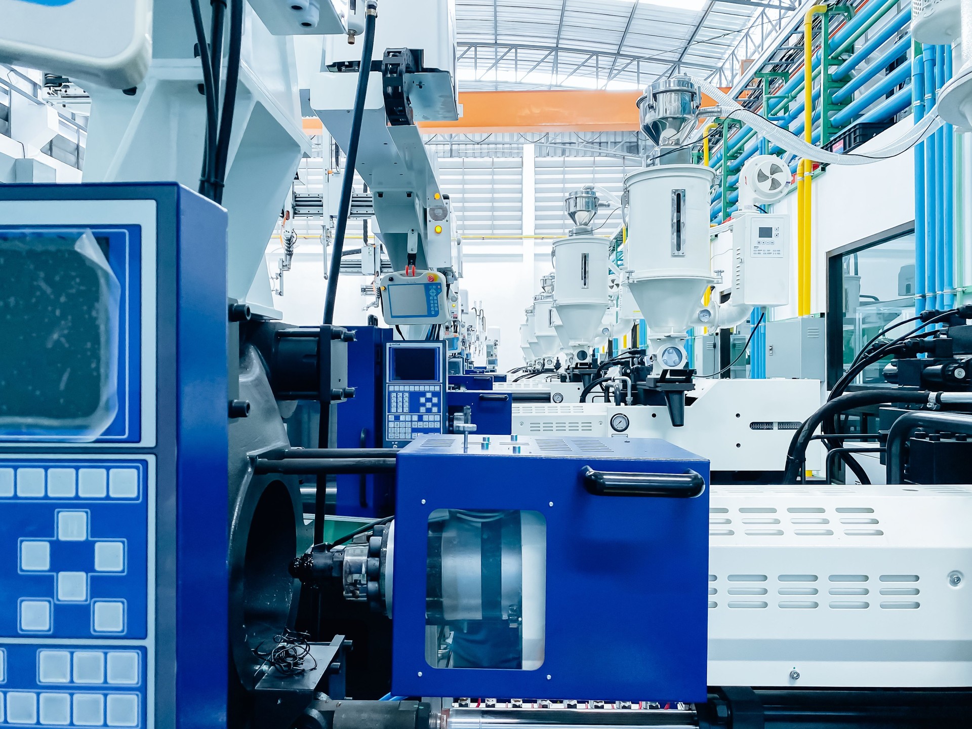 High-tech plastic injection molding machines lined up in a modern factory.